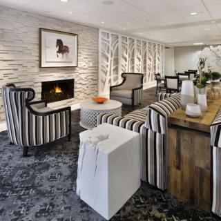 A modern living room featuring striped furniture, a cozy fireplace, and elegant artwork.