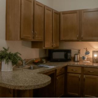 A cozy kitchen with wooden cabinets and a granite countertop featuring a microwave, sink, and small appliances.