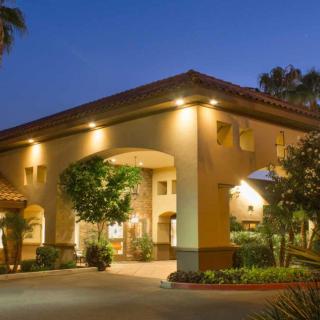 A well-lit building entrance at night, featuring an archway and surrounding greenery.