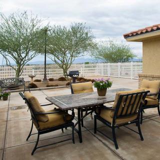 An inviting outdoor patio area with a table and chairs, surrounded by plants and trees under an overcast sky.