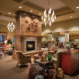 A cozy lounge area with warm lighting, featuring a central fireplace and comfortable seating arrangements.