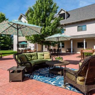 A spacious outdoor patio with comfortable seating and umbrellas in front of a house.