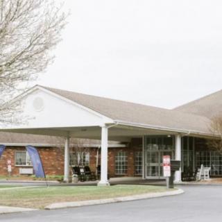 A brick building with a covered entrance and adjacent parking area.
