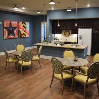 A modern kitchen and dining area with artwork on the walls, featuring a seating arrangement and wooden flooring.