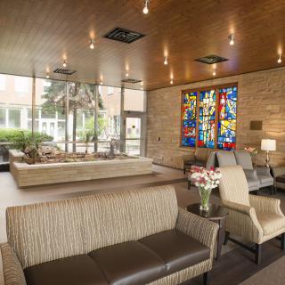 A modern lobby with comfortable seating and a stained glass window feature.
