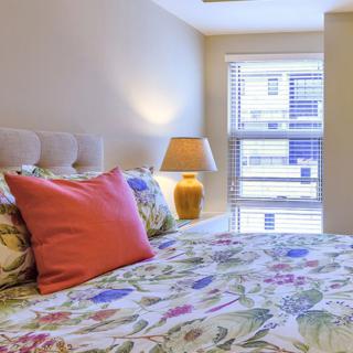 A cozy bedroom with floral bedding and a warm lamp by the window.