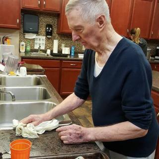 An elderly person cleaning a kitchen counter.
