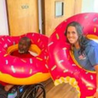 Two people having fun with giant inflatable donut floats indoors.