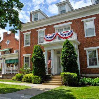 A beautifully adorned brick building with patriotic decorations, surrounded by lush landscaping.