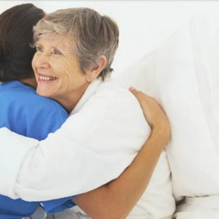 An elderly person hugging a caregiver, showing support and affection.