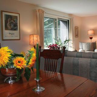 A cozy living and dining area with flowers on the table and comfortable seating by the window.