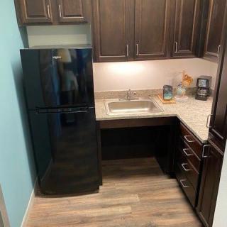 A modern kitchen with dark cabinets and a black refrigerator.