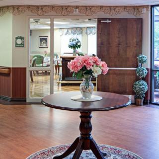 A welcoming lobby with a round table adorned with pink flowers in a vase.