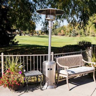 A patio heater beside a bench in a serene outdoor setting.