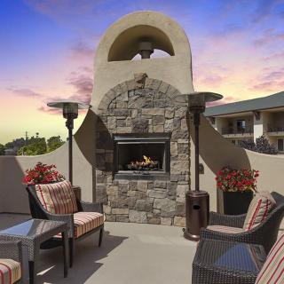 A cozy outdoor patio with a stone fireplace and comfortable seating at dusk.