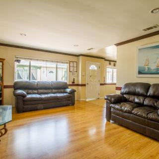 A bright and spacious living room with wooden flooring and comfortable sofas.