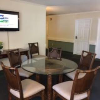 A simple dining or meeting area with a glass-top table and five chairs.