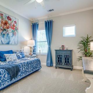 A cozy bedroom with a blue and white color scheme, featuring elegant decor and a floral painting.
