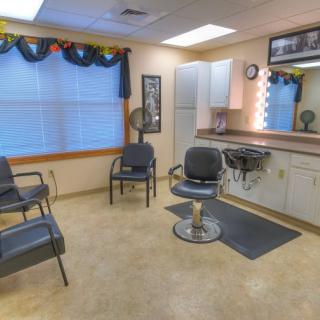 A cozy and well-lit hair salon interior featuring a barber chair, mirrors, and a small waiting area.