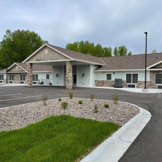 A modern building with a landscaped entrance and parking lot on an overcast day.