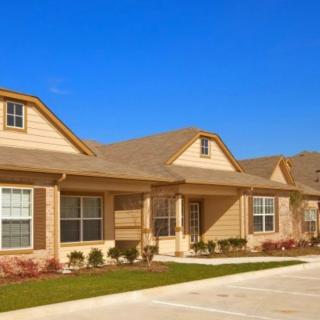 Suburban residential house with a driveway under a clear blue sky.