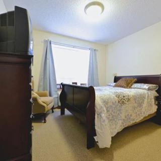A cozy bedroom featuring a wooden bed, armchair, and television.