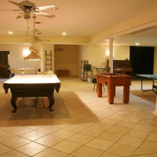 A spacious game room featuring a billiards table, foosball table, and ping pong table.