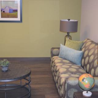 A cozy living room with a patterned sofa, decorative pillows, a modern lamp, and a round coffee table featuring a small globe.