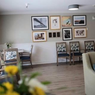 A cozy seating area with framed artwork on the wall and a table with chairs, accented by fresh flowers.