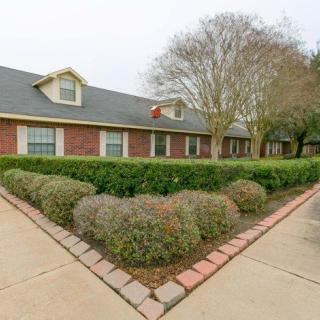 A brick house with manicured shrubs and a paved walkway.