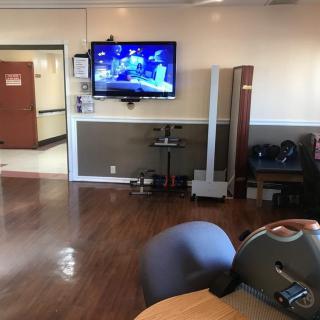 A lounge area featuring a television, chairs, and wooden flooring.