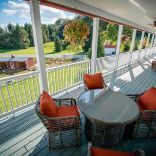 A spacious porch with comfortable seating overlooks a scenic countryside landscape.