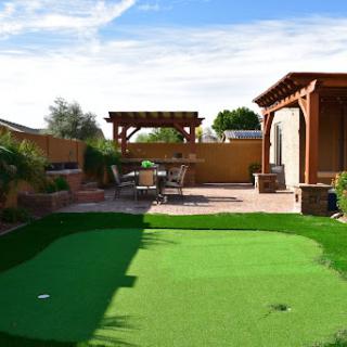 A beautifully designed backyard featuring a putting green, stylish patio, and a pergola for outdoor relaxation.