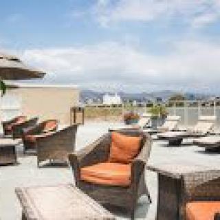 A rooftop patio with wicker chairs and umbrellas on a sunny day.