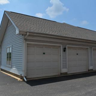 A residential building featuring multiple garage doors with a paved driveway.