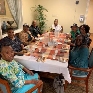 A group of people gathered around a dining table, smiling and enjoying their time together indoors.