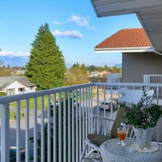 A cozy balcony with a table and chair overlooking a scenic neighborhood view.