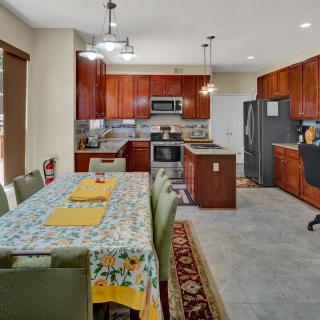A spacious kitchen and dining area featuring wooden cabinets, modern appliances, and a large dining table with a floral tablecloth.