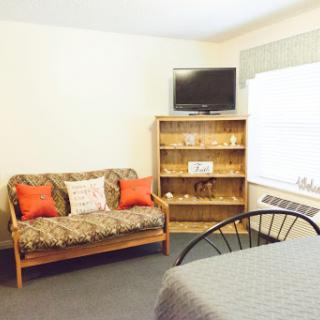A cozy living space featuring a sofa, television, and shelving.
