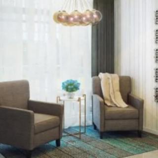 A cozy living room setup with two armchairs, a side table, and a modern pendant lamp.