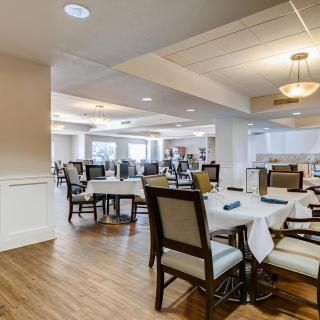 A spacious dining area with elegantly set tables and comfortable chairs, featuring ambient lighting and a polished interior.