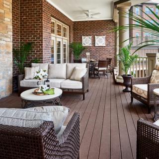 A cozy outdoor patio with wicker furniture and lush green plants.