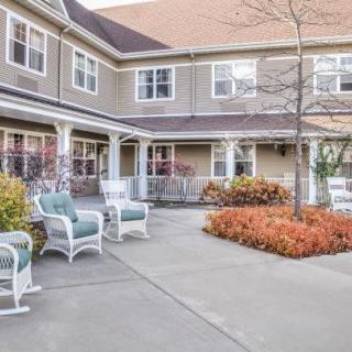 A peaceful courtyard with outdoor seating and well-maintained landscaping, surrounded by a two-story building.