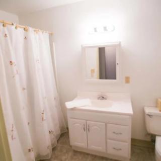 A clean and simple bathroom featuring a white vanity, shower curtain, and modern lighting.