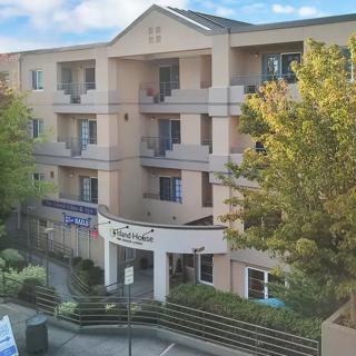 A view of a multi-story apartment building featuring balconies and surrounded by trees.
