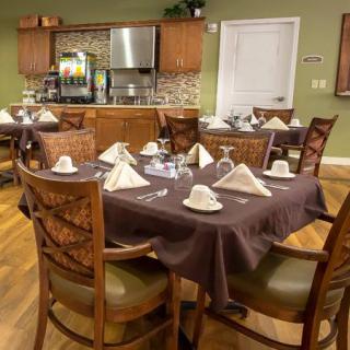 A neatly arranged dining room with tables set for guests, featuring elegant table settings and comfortable chairs.