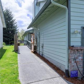 A sunny view of a house exterior with a paved sidewalk and adjacent lawn.