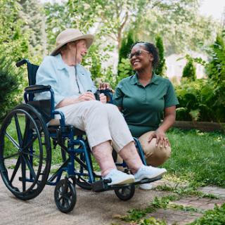 A caregiver and an elderly woman share a joyful moment in the garden, highlighting the warmth of companionship and support.