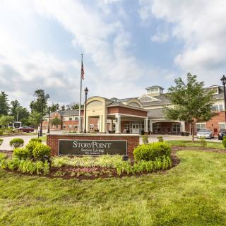 Front view of a hospital with manicured landscaping and a cloudy sky.