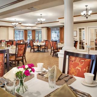 An elegant dining room setup with neatly arranged tables and chairs, adorned with vases of flowers.